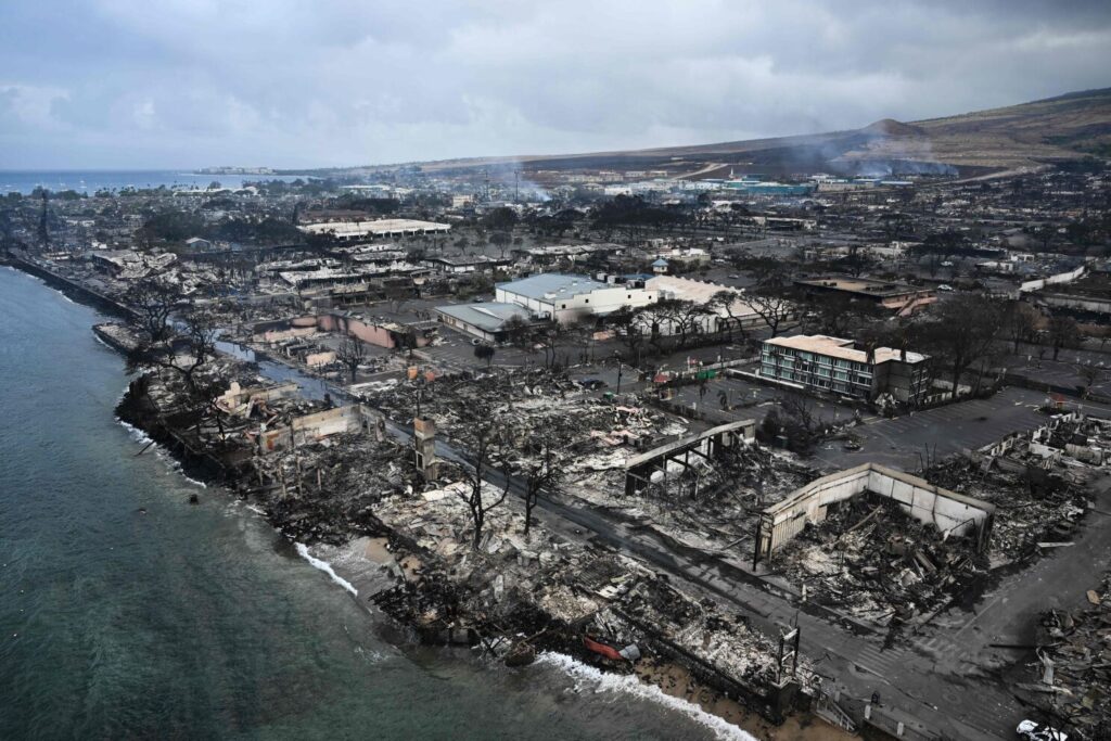 Taken from the skies on August 10, 2023, a sweeping aerial view unveils the aftermath of destructive wildfires in western Maui, Hawaii. The heart-wrenching image portrays a waterfront once adorned with homes and buildings, now reduced to smoldering ruins in Lahaina. The relentless blaze, which erupted in the early hours of August 8, voraciously consumed vast expanses of land, casting the lives of 35,000 individuals, as well as numerous residences and businesses, into a perilous state. A solemn proclamation from the Hawaii Emergency Management Agency accentuated the gravity of the situation, emphasizing the urgent necessity for intervention. (Credit: AFP via Getty Images)